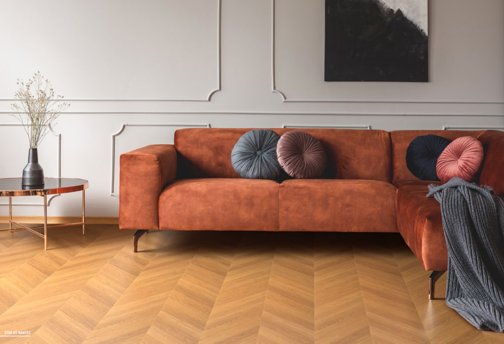 divano arancione con pavimento vinilico effetto legno a spina